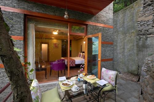 a patio with a table and chairs and a bedroom at Regenta Inn by Riverside Manali in Manāli