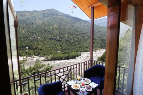 a balcony with a view of a river and mountains at Regenta Inn by Riverside Manali in Manāli