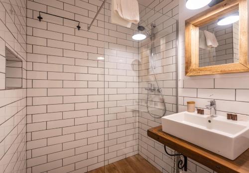 a white tiled bathroom with a sink and a mirror at Pensiunea Belvedere in Tîrgu Neamţ
