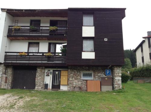 a house with a black roof and a building at Ubytování v soukromí Kouba in Pec pod Sněžkou