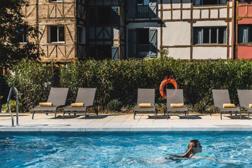 a person swimming in a pool in front of a house at Hotel Zubieta in Lekeitio