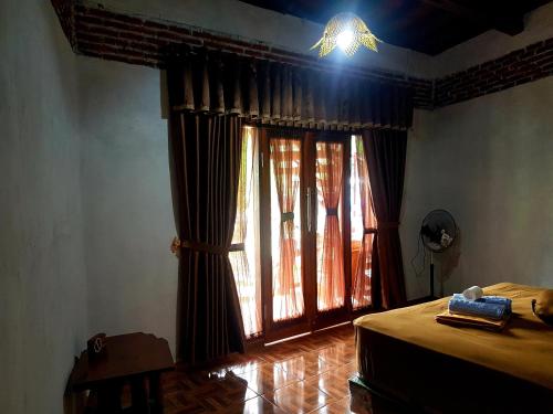 a bedroom with a bed and a window with curtains at Green Travelodge Bukit Lawang in Bukit Lawang