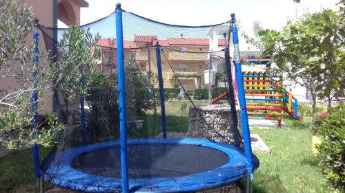 a blue trampoline in a yard with a playground at Apartments Rajka in Lopar