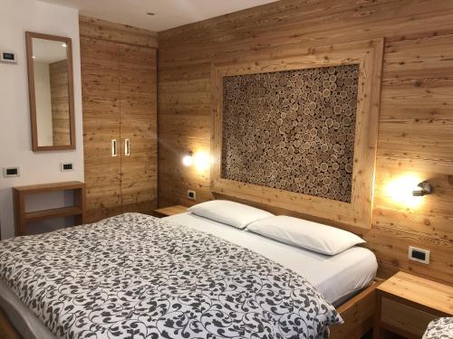 コンメッツァドゥーラにあるAppartamenti Penasa Renatoの木製の壁のベッドルーム1室(大型ベッド1台付)
