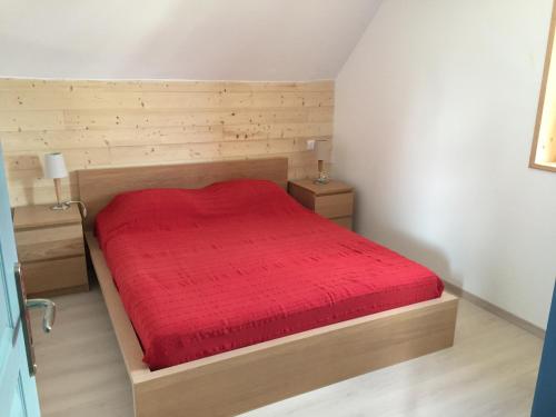 a bedroom with a wooden bed with a red bedspread at APPT T2 PROCHE PLAGE in Plouharnel