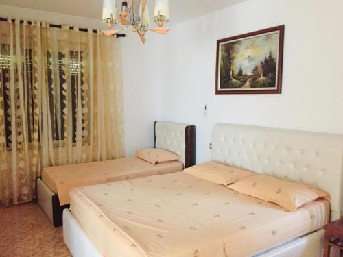 a bedroom with two beds and a picture on the wall at Jemin Apartment in Berat