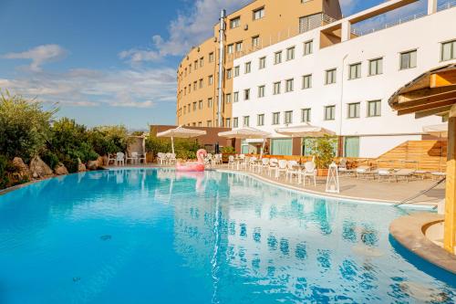 een groot blauw zwembad naast een gebouw bij Mercure Olbia in Olbia