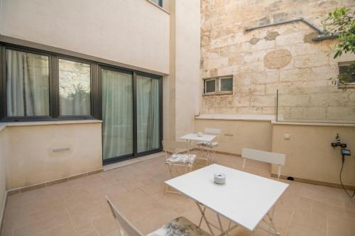 Habitación con mesas, sillas y pared de ladrillo. en Sindic Hotel - Adults Only, en Mahón