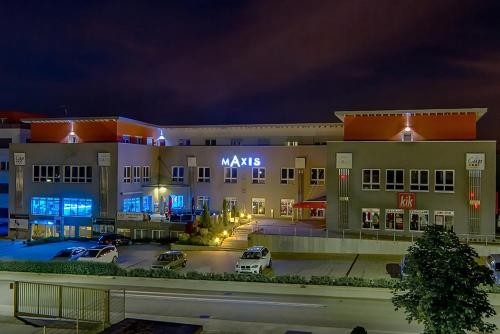 un grand bâtiment avec des voitures garées dans un parking dans l'établissement Hotel Maxis, à Karlsbad