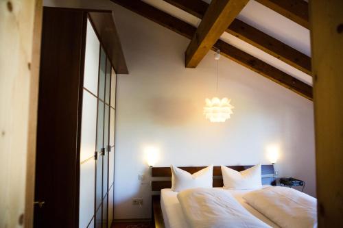 1 Schlafzimmer mit 2 Betten mit weißer Bettwäsche und einem Kronleuchter in der Unterkunft Gästehaus Rössler in Brannenburg
