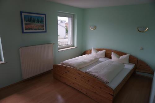 a bedroom with a wooden bed with white pillows at Hotel am Bahnhof in Waren