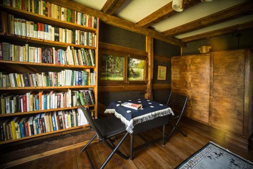 a room with a table and chairs in a library with books at Grenlanda in Ulanów
