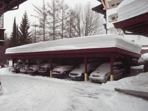 a parking lot with cars covered in snow at Appartements Holiday in Ellmau