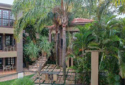 a house with palm trees in front of it at Waterfalls Boutique Hotel in Pretoria