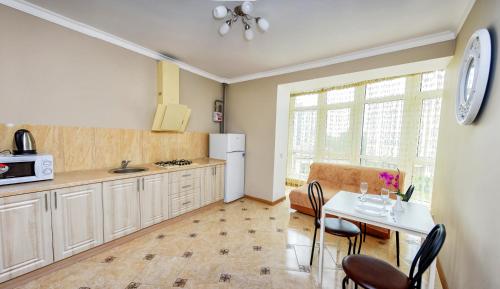 a kitchen with a table and chairs and a refrigerator at Apart Reserve Sloboda Klassik in Ivano-Frankivsk