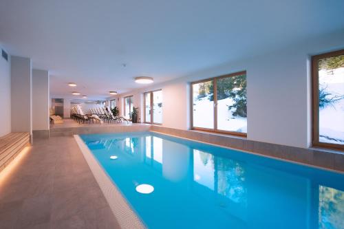 a swimming pool with blue water in a house at Hotel Boè Sport and Nature in Arabba