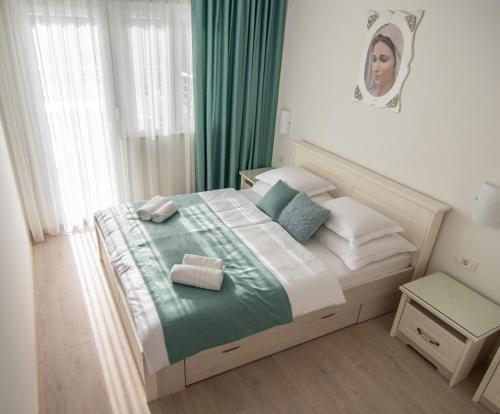 Schlafzimmer mit einem Bett mit grüner Bettwäsche und Kissen in der Unterkunft Gloria Apartments 1 in Međugorje