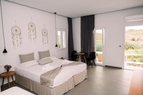 a white bedroom with a bed and a large window at Abelos Mykonos in Mikonos