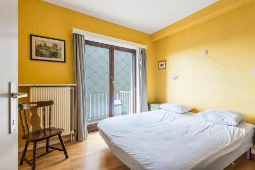 ein Schlafzimmer mit einem Bett, einem Stuhl und einem Fenster in der Unterkunft Ascot 5de in Zeebrugge