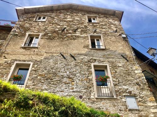 a stone building with windows and flowers on it at B&B Convivium in Stazzema