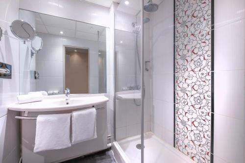 a white bathroom with a sink and a shower at Mercure Rouen Centre Champ de Mars in Rouen