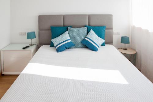 um quarto com uma cama branca e almofadas azuis em Alto das Marinhas em Aveiro