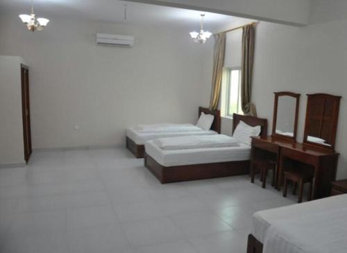 a room with two beds and a table and a mirror at Al Sqlawi Hotel Apartments in Sur