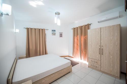 una camera con letto, porte in legno e finestra di Jade Apartment a Flic-en-Flac