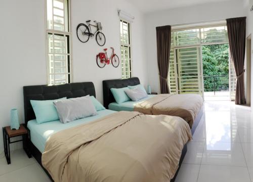 two beds in a bedroom with a bike on the wall at De Nest Holiday home in Bayan Lepas
