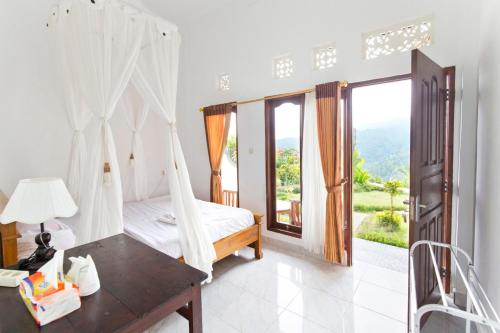een slaapkamer met een bed en een groot raam bij Aris Homestay and Warung Made in Munduk