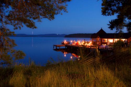 a dock with a house on a lake at night at Herranniemi Guesthouse in Vuonislahti