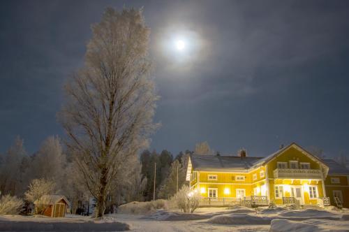 a large yellow house in the snow at night at Herranniemi Guesthouse in Vuonislahti