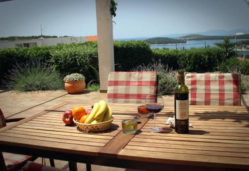 a picnic table with a basket of fruit and a bottle of wine at Apartments Giardino in Hvar