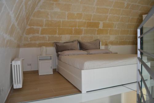 Ce lit se trouve dans une chambre dotée d'un mur en briques. dans l'établissement BRG APARTMENTS, à Matera