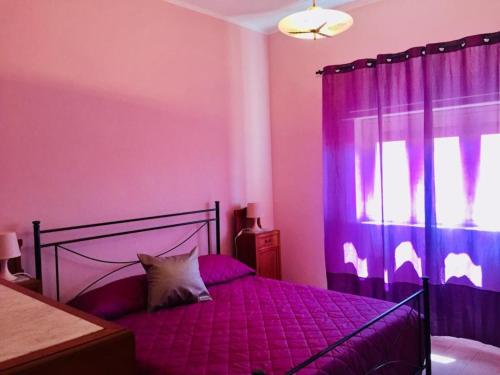 Un dormitorio con una cama con sábanas moradas y una ventana en My lovely Home, en Noto