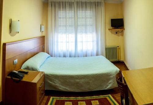 a bedroom with a bed and a desk at Hotel Mabú in Ourense