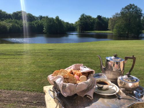 a basket of food on a table next to a lake at Château du Maurier in La Fontaine-Saint-Martin