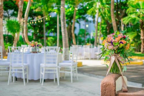 a group of tables with white chairs and flowers at Hotel Maya Caribe Faranda Cancún in Cancún