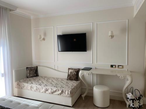 a white room with a desk and a tv on the wall at Hotel Ca' D'Oro Tre Stelle Superior Adults only in Bibione
