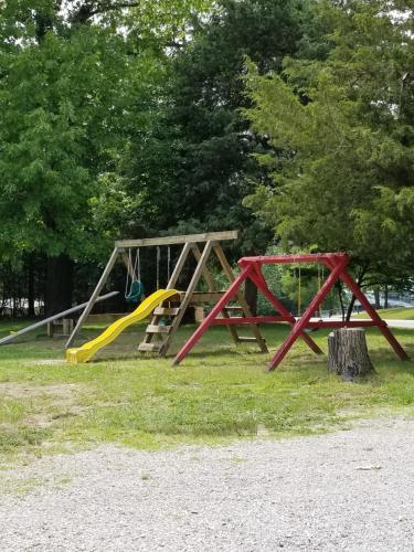 a playground with two swings and a slide at The Cottage Resort in Branson