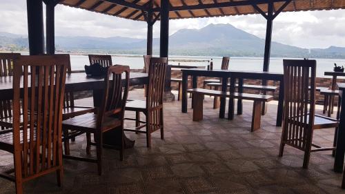 a table and chairs with a view of the water at Batur Green Lakeview in Kintamani Bali in Kintamani