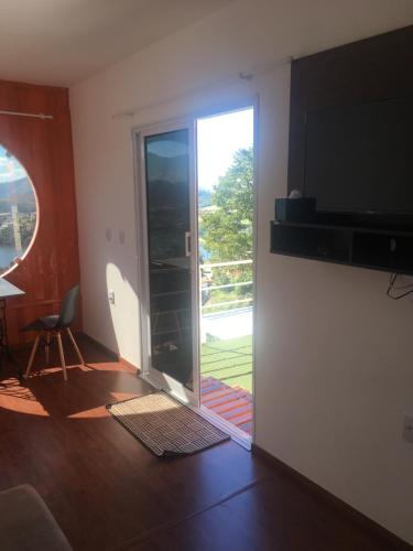 a living room with a sliding glass door and a television at Amsterdam lofts 3 in Poços de Caldas