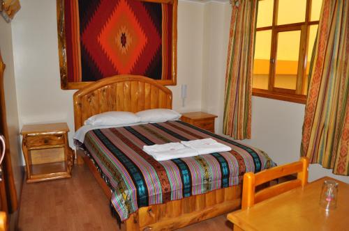 a bedroom with a wooden bed and a table at Hotel Santafe Inn in Otavalo