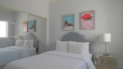 a white bedroom with two beds and a mirror at The Hermitage at Napeague in Amagansett