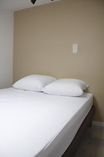 - un lit avec 2 oreillers blancs dans l'établissement Petit nid à 50m de la plage au coeur de Fouras, à Fouras