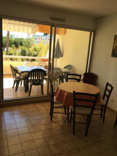 a dining room with tables and chairs and a patio at Agréable F3 sur Carnon-plage à 10 mn de Montpellier in Carnon-Plage