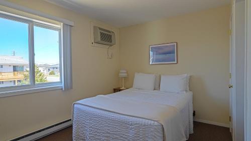 a white bedroom with a bed and a window at Montauk Oceanside Suites in Montauk