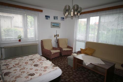 a bedroom with a bed and two chairs and windows at Ubytování v Proseči in Proseč