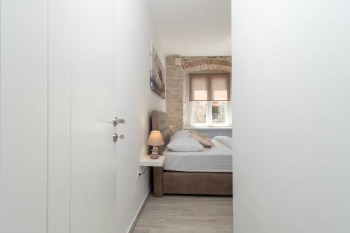 a bedroom with a bed and a window at Studios Kadena Trogir - 18th century stone house in Trogir