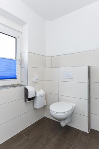 a white bathroom with a toilet and a window at Ferienwohnung Haus zum Seehund mit Pool und Frühstücksoption in Bensersiel